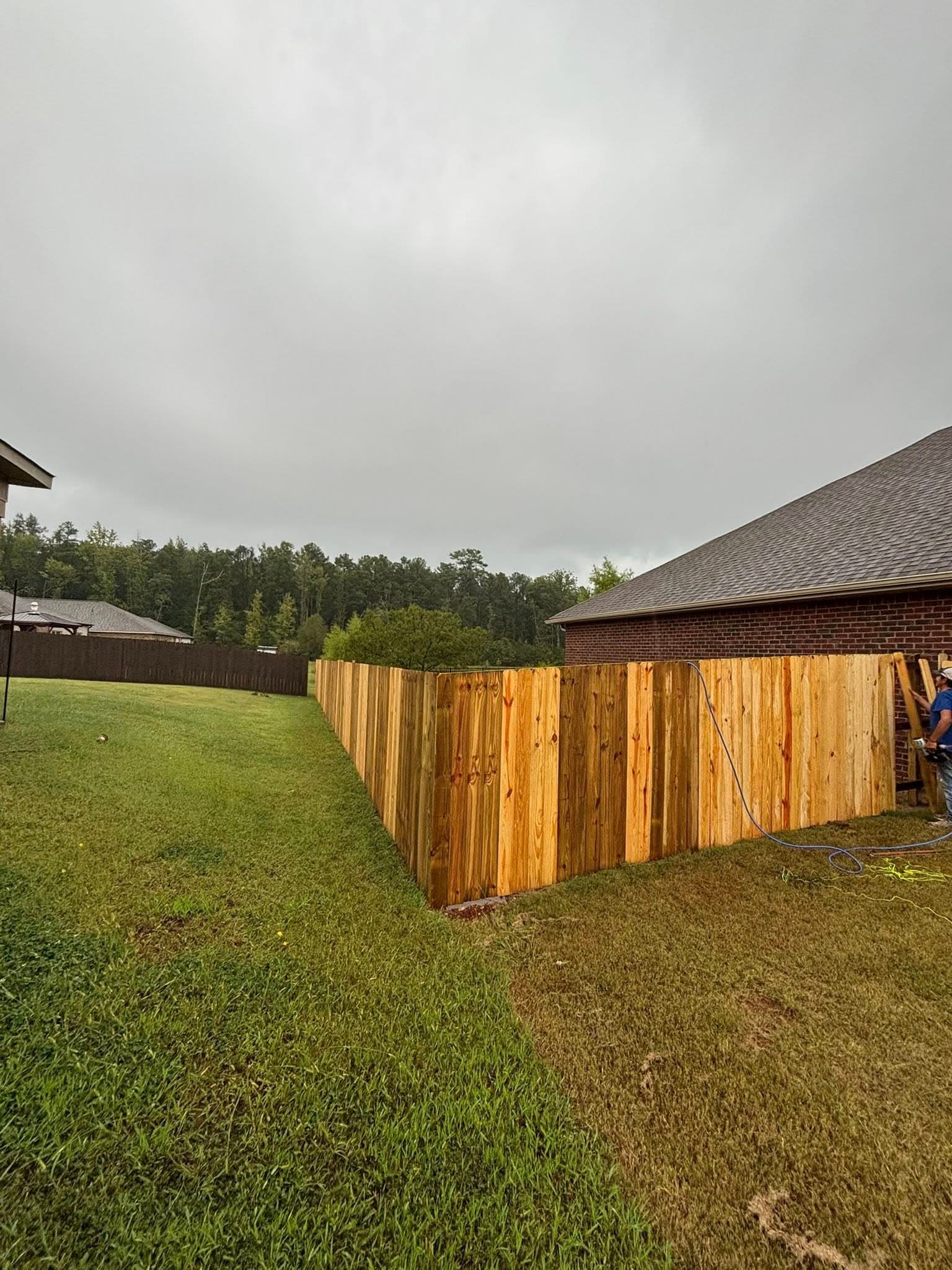 Newly built wooden privacy fence surrounding backyard residential property in Alabama.